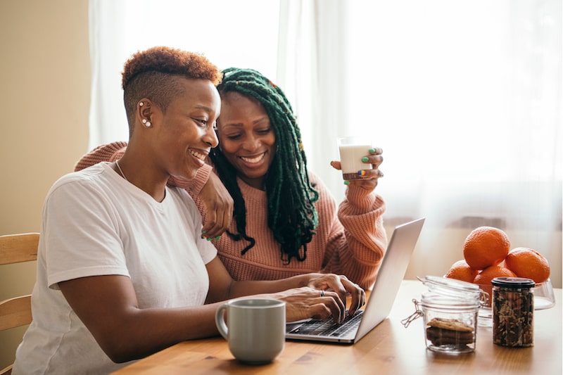 two woman laughing while looking at the computer