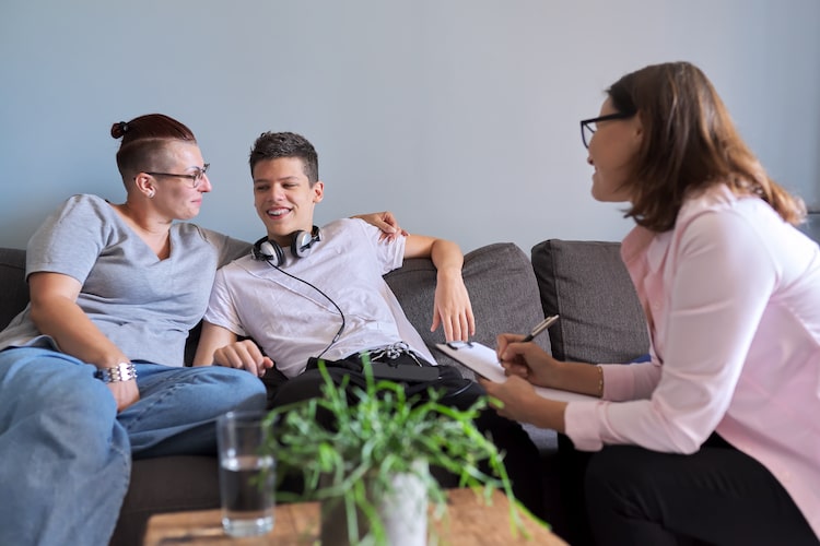 two teenage guys sitting on a couch talking to a women therapist