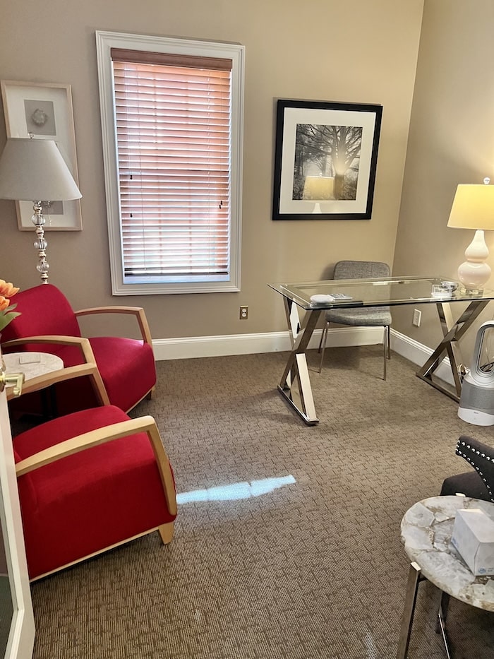 Inside an office with two red arm chairs and a glass desk