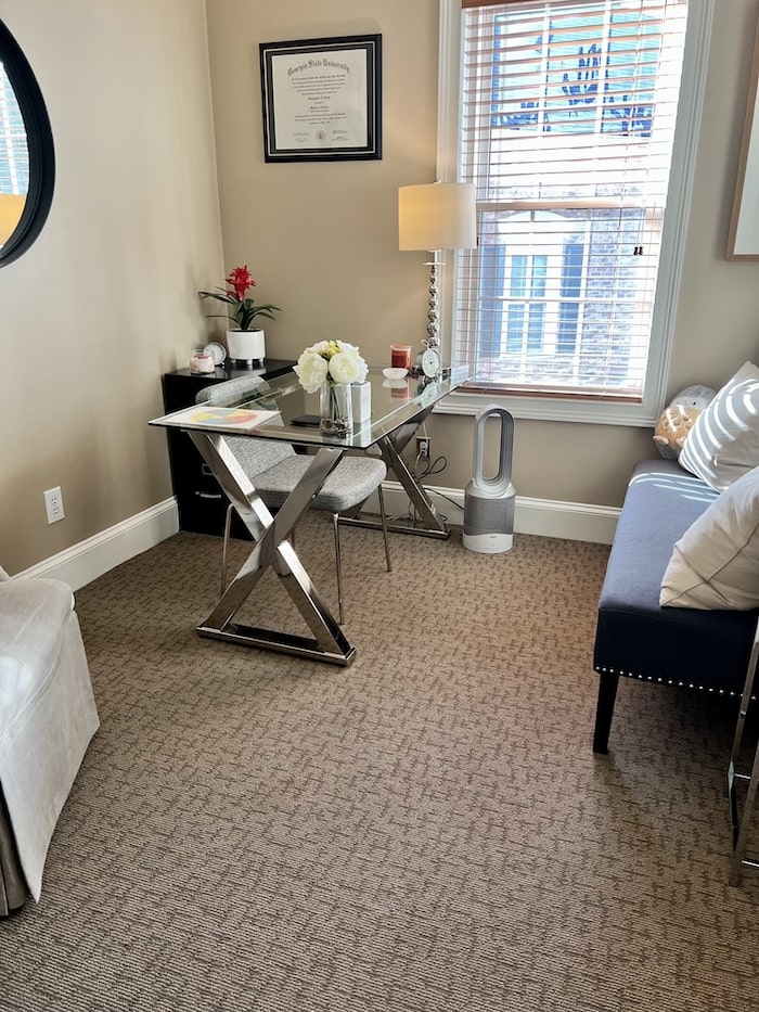 Office with black couch and pillows and a glass desk