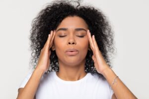 Woman breathing out with eyes closed and fingers at her temples